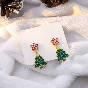 Macro shot of festive Christmas tree earrings with red stars on white fuzzy fabric