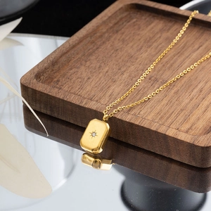 French vintage gold necklace featuring a rectangular star pendant on a dark wooden tray