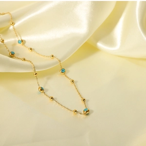 Detail of 18K gold plated chain necklace with turquoise blue evil eye beads on silk