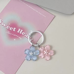 Close-up of pink and blue resin cherry blossom keychains with white painted metal rings