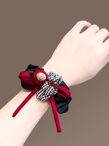 Detailed shot of red and black checkered bear scrunchie with satin bow on wrist