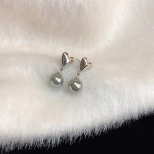 Détail de boucles d'oreilles cœur en argent avec perles grises sur peluche blanche