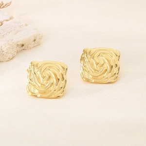 Close-up of golden square earrings featuring elegant spiral embossed texture