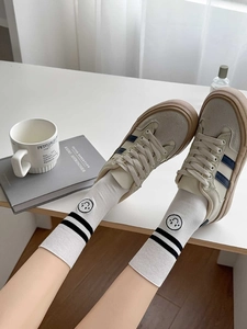 Detail of white cotton socks with navy blue stripes and smiley face logo on the ankle