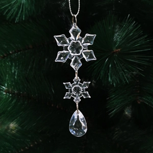 Sparkling crystal snowflake and teardrop ornaments hanging on a green Christmas tree