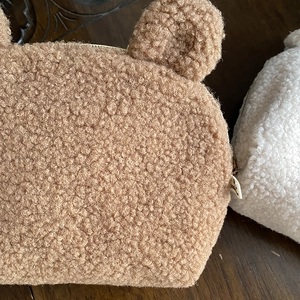 Cute teddy plush cosmetic bags with bear ears in brown and white shown on wooden desk