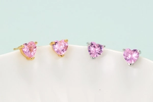 Gold and silver heart stud earrings with pink zircon in minimalist three-prong setting
