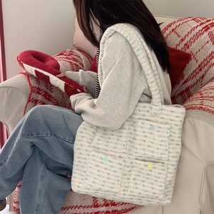 Detail of colorful plush tote bag with four unique buttoned pockets worn by model