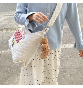 White quilted tote with house embroidery and teddy bear charm on model in street