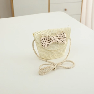 Close-up of cream woven straw bag for kids featuring a brown polka dot bow and lace trim
