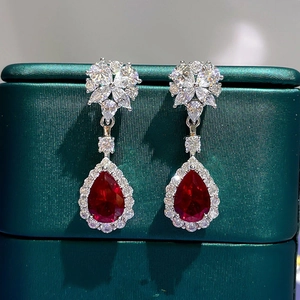 Detail of teardrop ruby earrings with pear-cut gemstones and diamond halo in silver