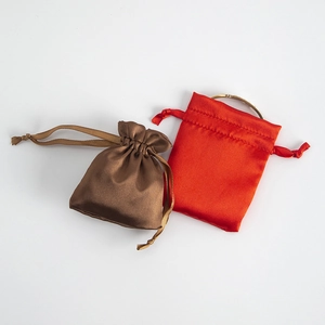 Flat lay of brown and red satin drawstring gift bags for jewelry storage on white background