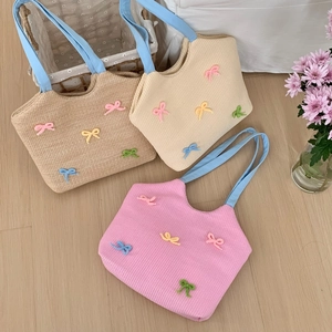 Detail of woven straw tote bags with colorful bow accents and sky blue ribbon handles