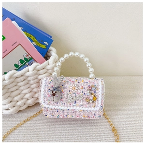 Detail of pink tweed girl's bag featuring a pearl handle, rabbit decor and gold chain
