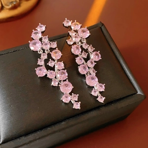 Macro shot of pink zircon cluster tassel earrings on a black textured jewelry box