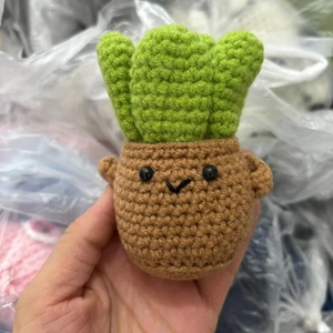 Detail of a handmade crochet cucumber plush with a funny expression and knitted texture