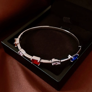 Detail of silver bangle with five vibrant gemstones in a black velvet jewelry box