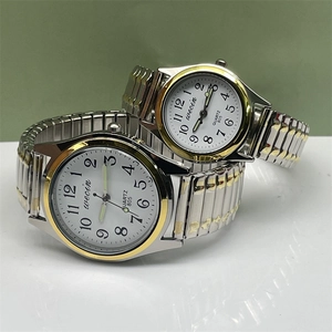 Close-up of quartz couple watches with gold-silver stretch bands and large numerals