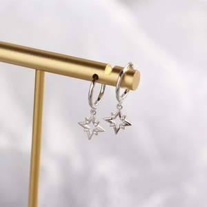 Detail of silver star earrings with cubic zirconia on a gold display stand