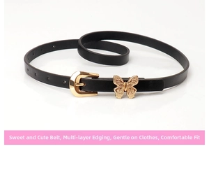 Detail of a thin black leather belt featuring a polished gold butterfly charm and horseshoe buckle
