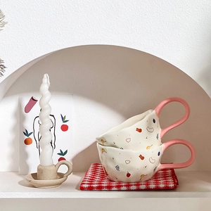 Detail of cream ceramic bear mugs with rabbit patterns on red checkered napkin