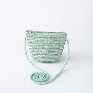 Detail of mint green straw bucket bag with woven shoulder strap and zipper closure