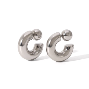 Close-up of chunky silver C-shaped stainless steel earrings with spherical backings