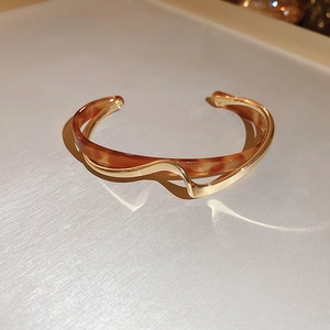Detailed view of gold plated wavy cuff bracelet with tortoiseshell pattern texture
