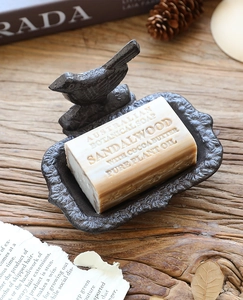 Macro shot of vintage cast iron bird soap dish and sandalwood soap on rustic wood