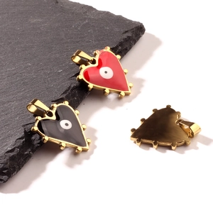 Gold stainless steel heart pendants with enamel evil eye designs on slate and white background