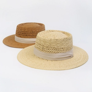 Detail of hollow woven straw boater hats in cream and caramel with satin ribbons