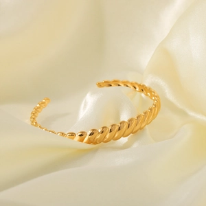 Minimalist 18K gold plated stainless steel C-shape twisted cuff bracelet on silk background