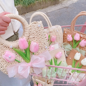 Close-up of woven straw handbag featuring delicate pink tulips and pearl decorations