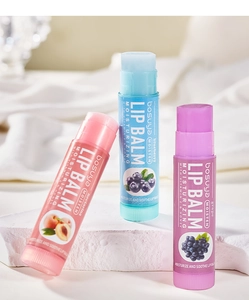 Three fruit-flavored lip balms with Vitamin E on a white textured stone surface