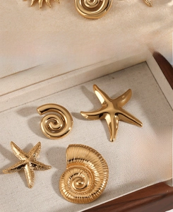 Detailed view of gold starfish and sea shell charms on a velvet jewelry display tray