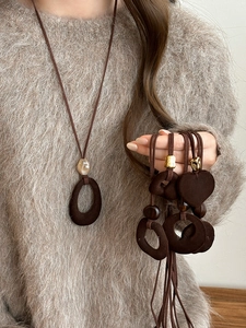 Detail of dark brown flocked geometric pendants on long sweater necklace chains