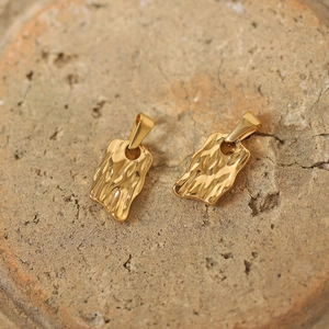 Detailed view of two vintage gold-plated titanium sun god pendants with wrinkled texture