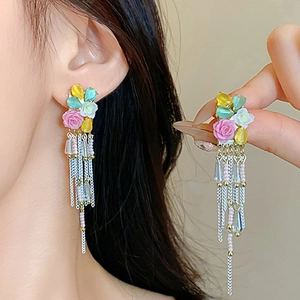 Close-up of long tassel earrings with colorful resin flowers and beaded silver chains