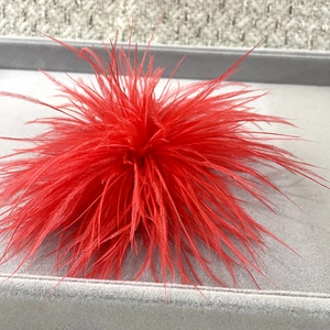 Macro detail of vibrant red ostrich feather brooch on a grey velvet display tray