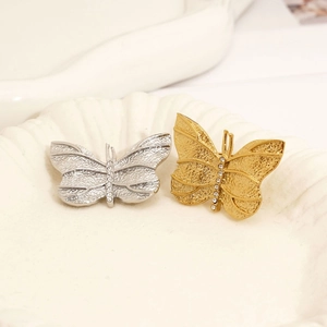 Elegant gold and silver butterfly brooches with crystal inlay on a ceramic tray