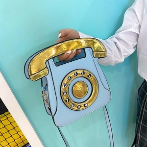 Detail of creative vintage telephone crossbody bag with metallic gold dial and blue PU leather
