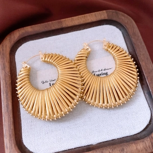 Detailed macro view of vintage gold hollow circular earrings on premium velvet texture
