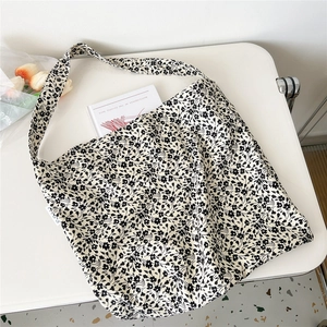 Detailed view of canvas tote bag featuring dense black floral patterns on white fabric