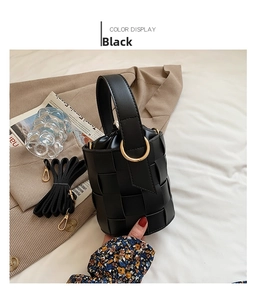 Detail of black woven bucket bag showing drawstring closure and gold metal buckle hardware