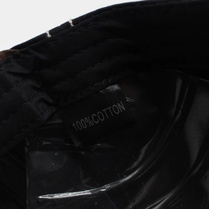 Close-up of the washing label showing 100% cotton fabric on a black baseball cap