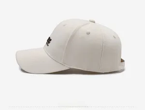 Detail view of cream cotton baseball cap with dark brown letter embroidery on the side