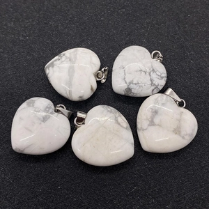 Detailed view of heart-shaped white turquoise pendants with natural grey veins on black surface