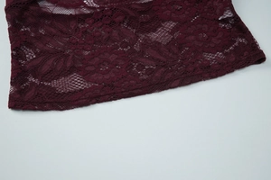 Detailed macro view of burgundy lace fabric showing elegant floral patterns and texture