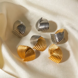 Macro detail of intertwined spiral earrings in gold and silver finish on silk