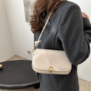 Elegant beige minimalist saddle bag with gold metal clasp and knotted strap detail